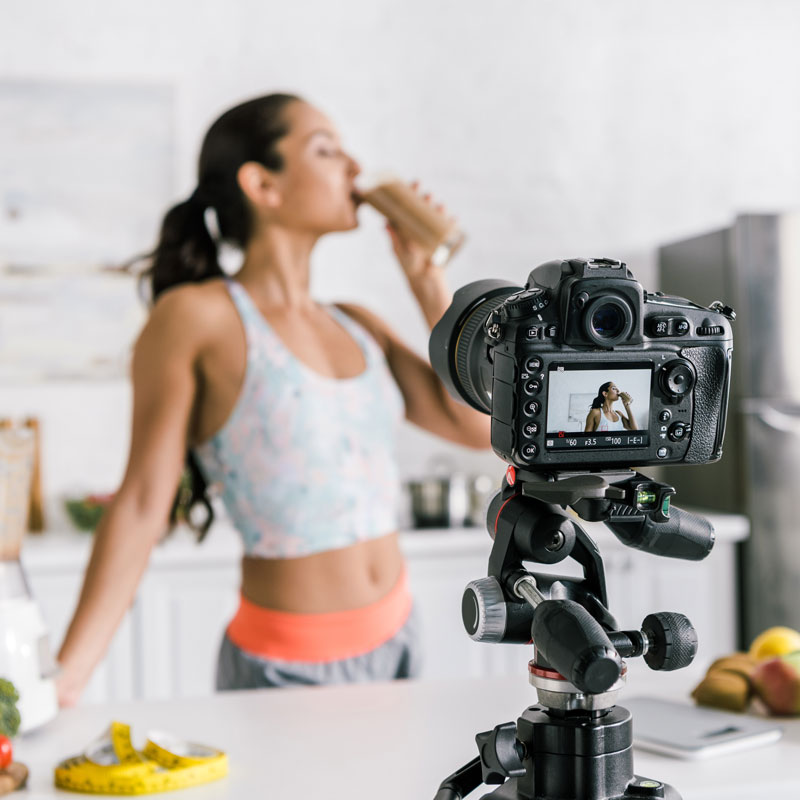 Woman filming herself drinking a healthy smoothie with NutriKane