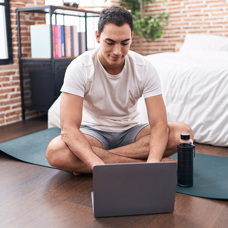 Young male sitting on yoga mat checking his MediKane Affiliate Program dashboard
